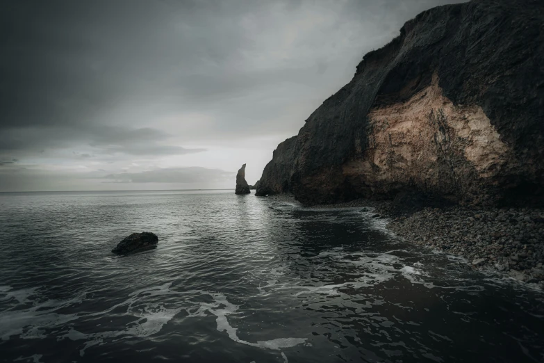 a rock face sits in the water near a cliff