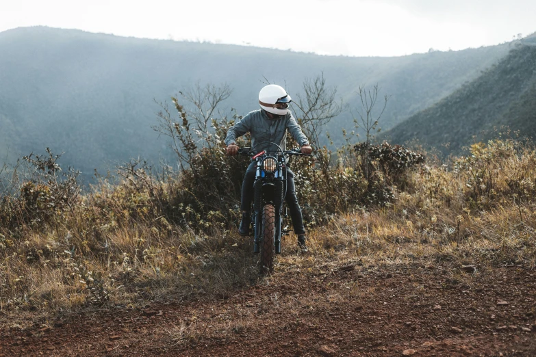 a man riding on the back of a bike down a dirt road