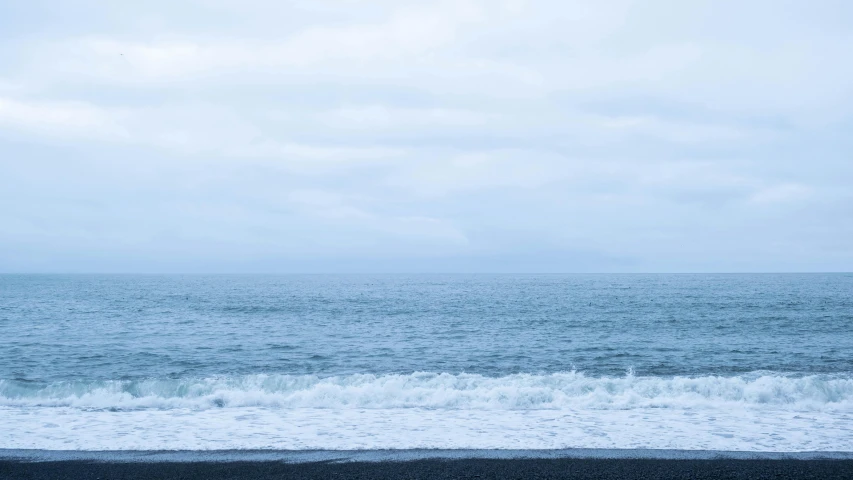 waves crashing on the sand on a cloudy day