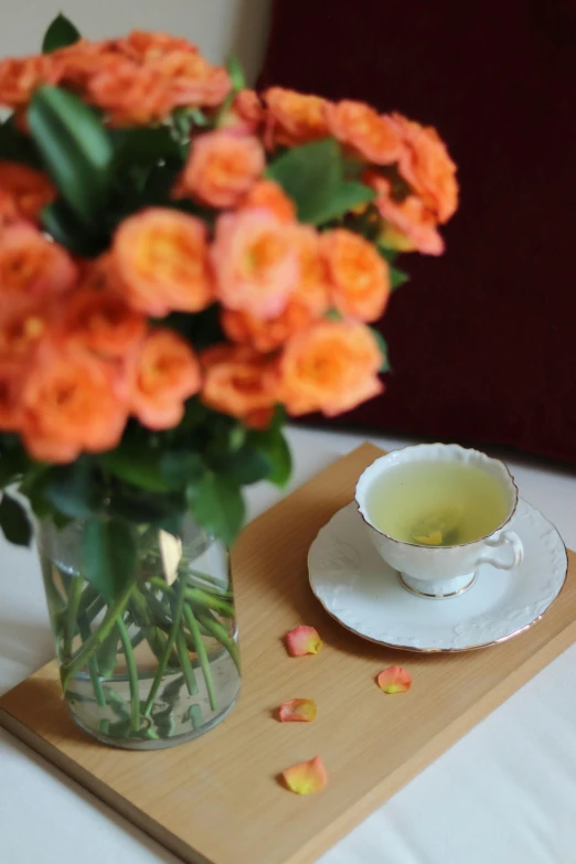 tea cup and saucer on wood board with flower arrangement