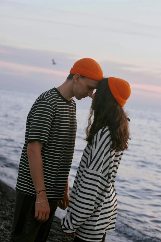 a young man and woman kissing near the water