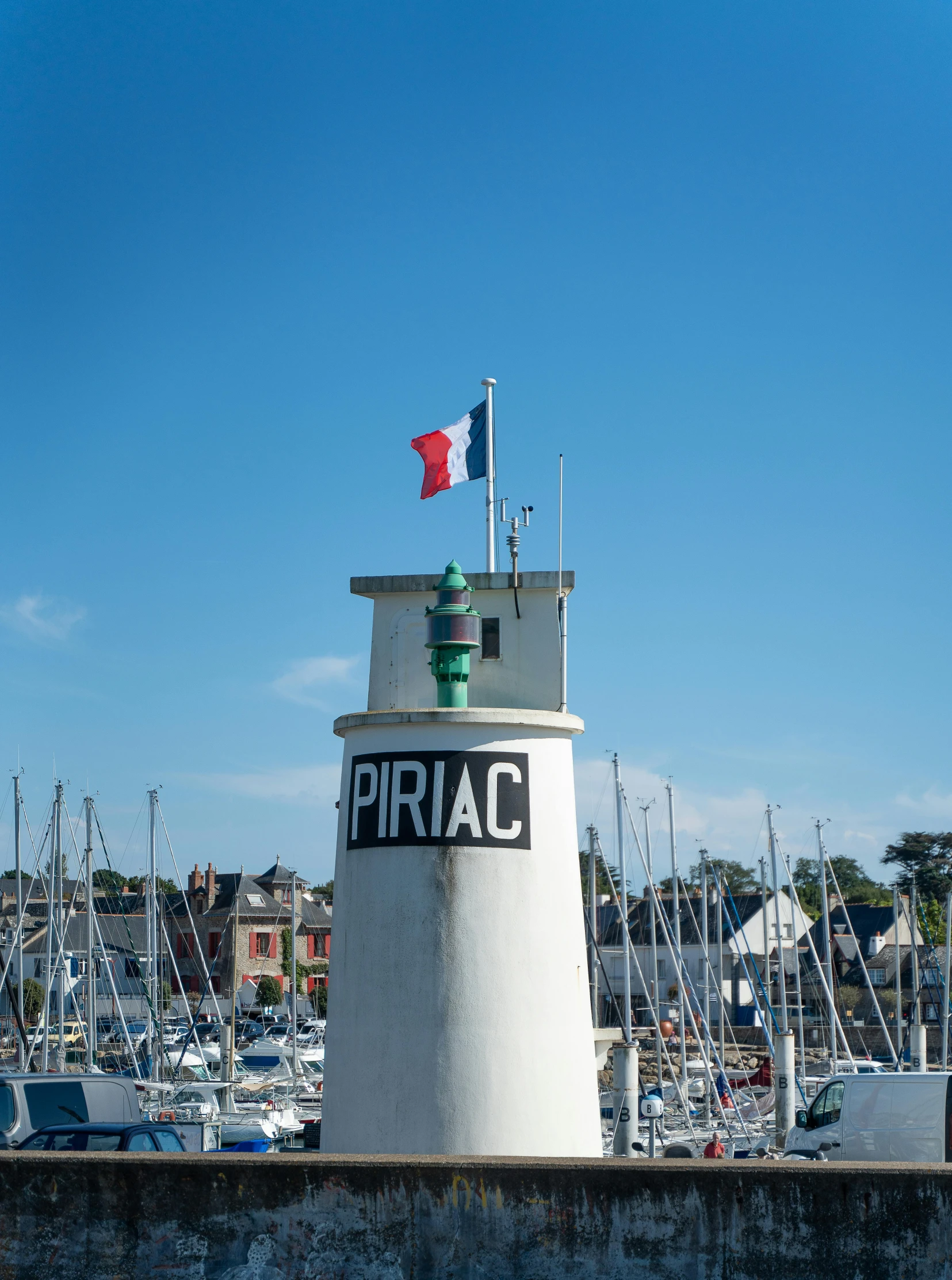 a white lighthouse on pier next to many boats