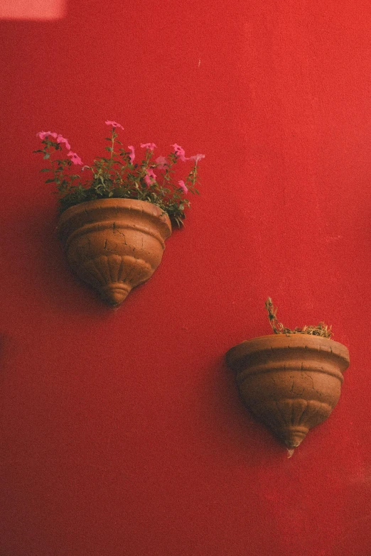 two pots that are sitting on a red wall