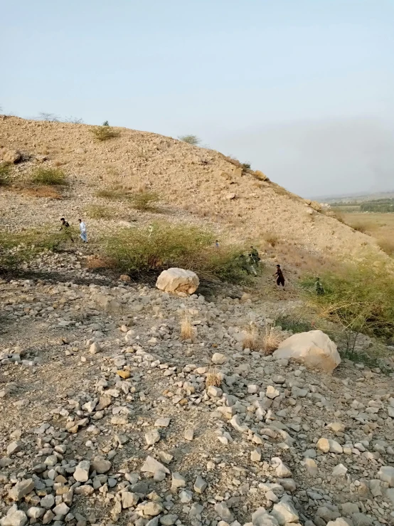 people walking uphill in the distance from a rocky slope