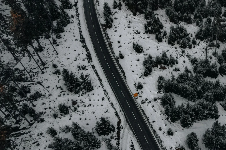 an aerial view of a road surrounded by snowy trees