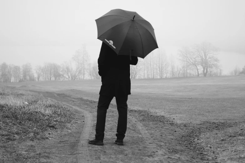 man standing on road in open field with umbrella