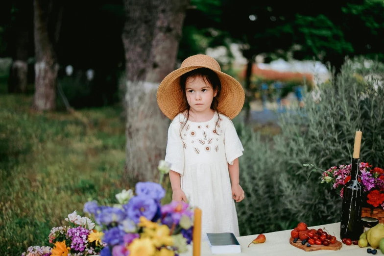 a girl wearing a hat near a table full of flowers