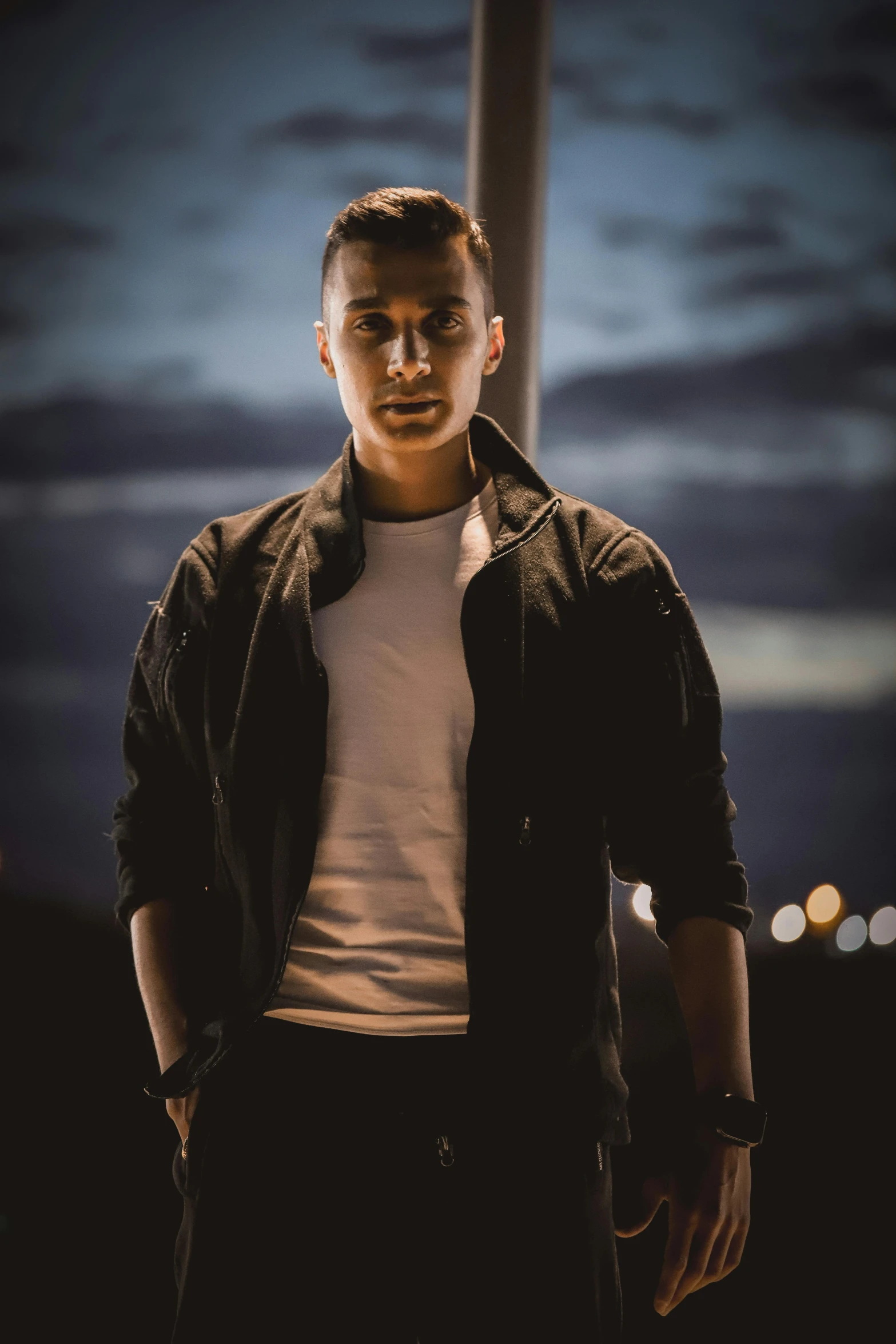 a man is standing in front of a cross at night