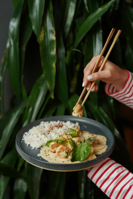 someone using chopsticks to eat rice and some vegetables