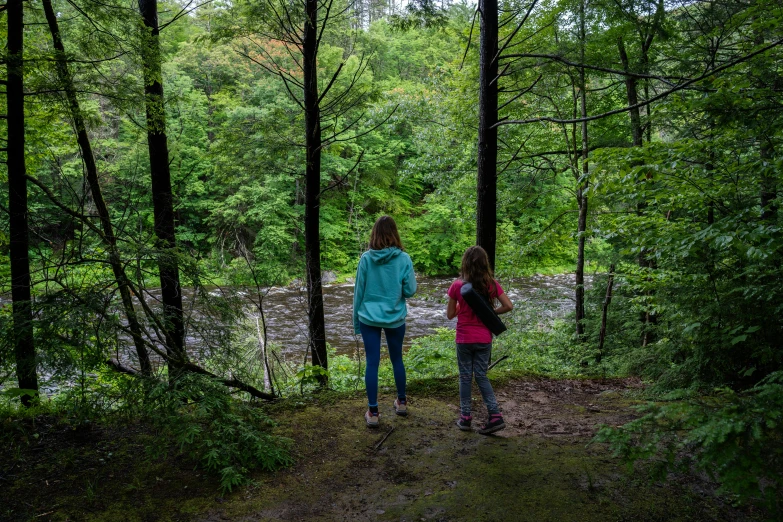 two women walk in the woods near a stream