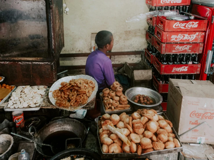 there is a man sitting in front of a fruit stand