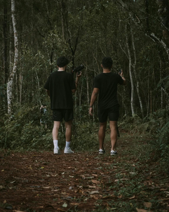 two men are walking on the woods in shorts