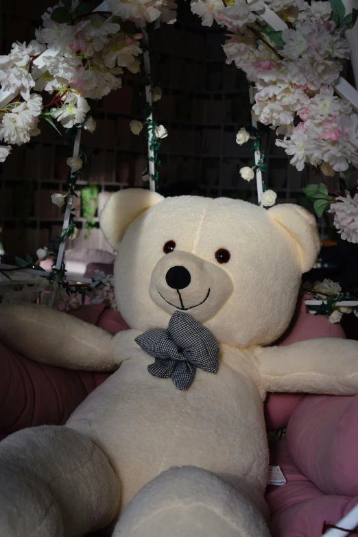 a white teddy bear is sitting with flowers