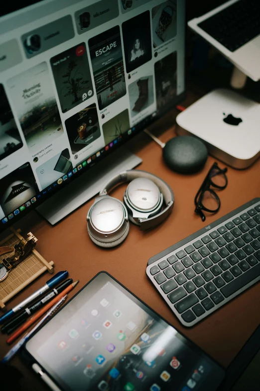 a laptop and phone, laptop computer, tablet and keyboard are on a desk