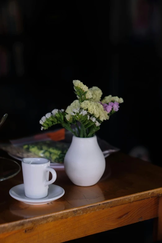 a white coffee cup with some flowers in the vase