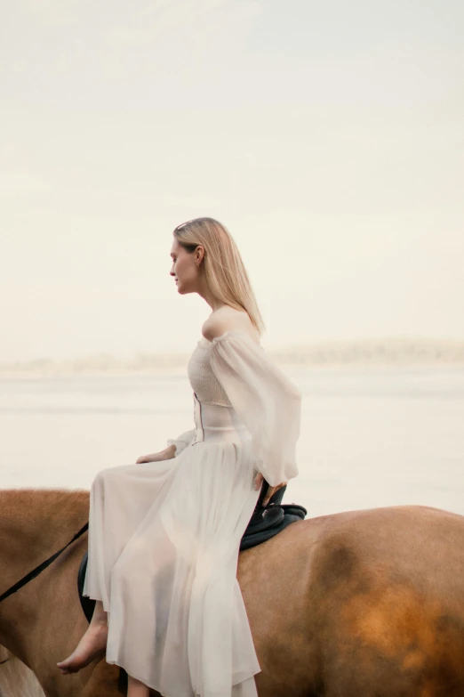 a woman sitting on a horse near the ocean