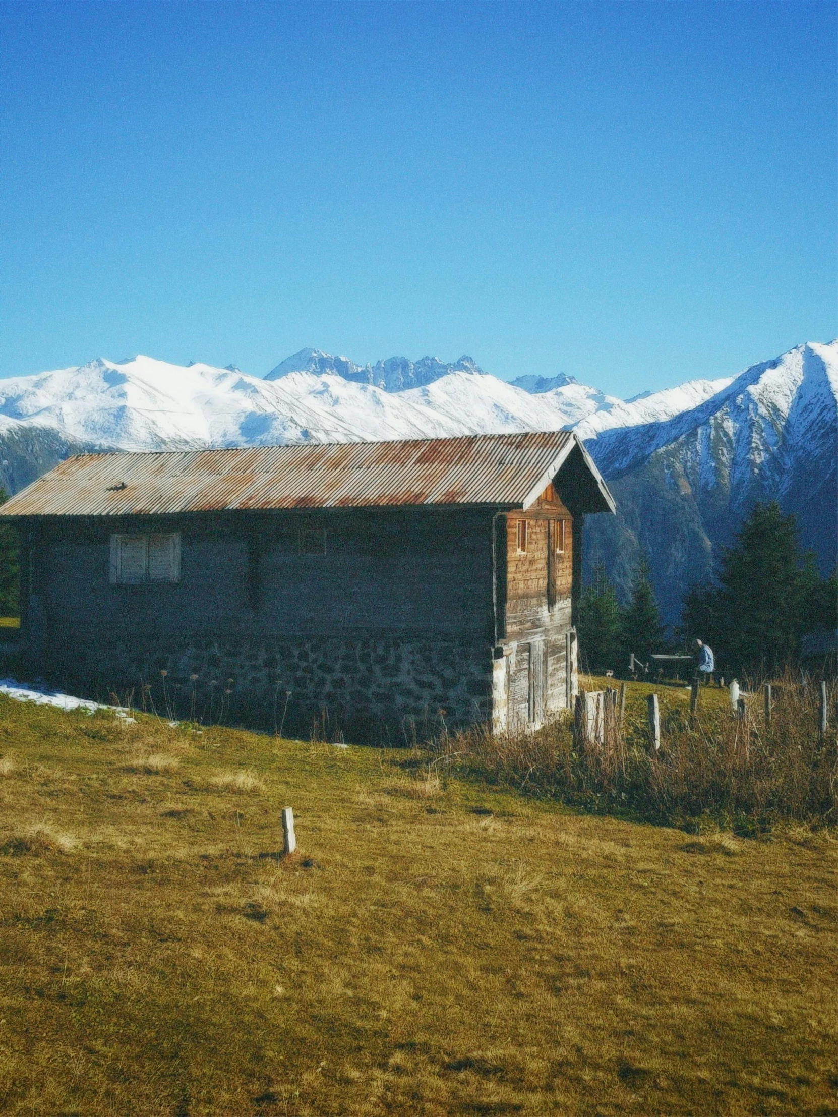 an old house on a hillside with mountains in the background