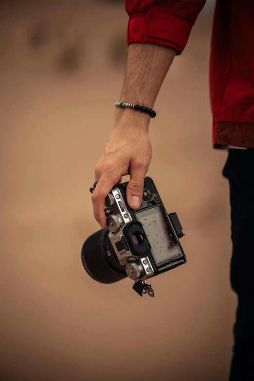 a man's hand holding an old fashioned camera