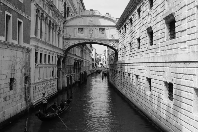 black and white pograph of an arched bridge spanning over a canal