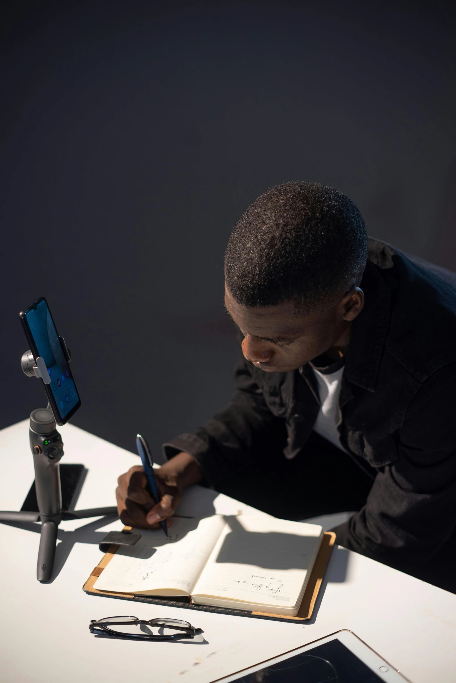 a young man sitting at a table signing an book