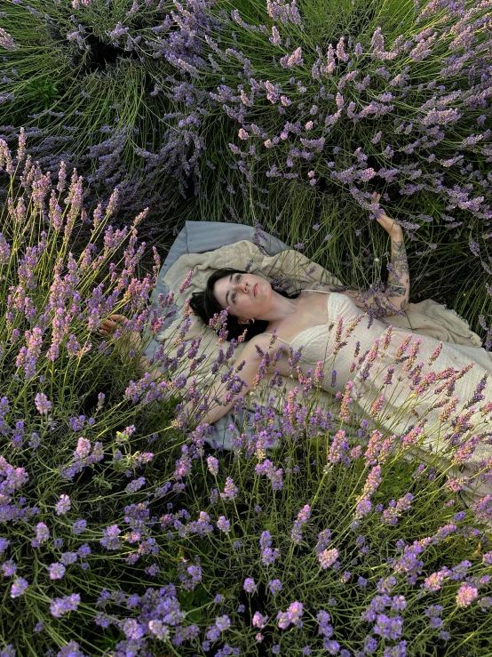 a woman is laying on her stomach in a field of flowers