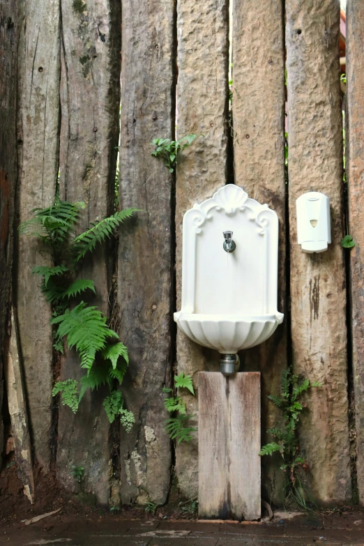 a water fountain against a weathered wood wall