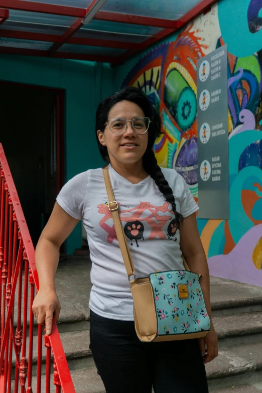 a woman standing by a staircase carrying a purse