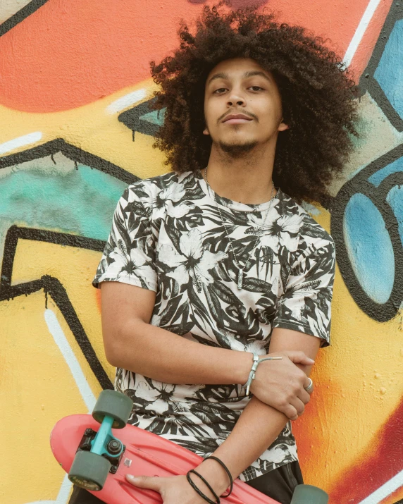 a person standing with a skate board in front of a wall covered in graffiti