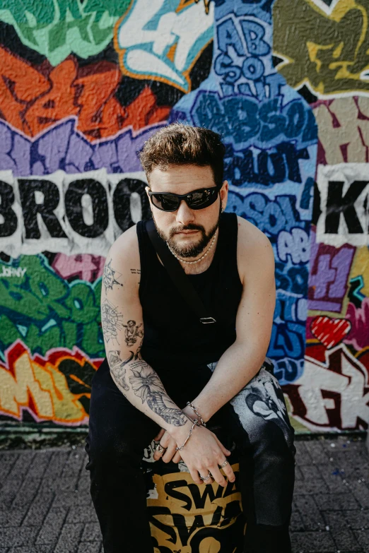 a man in black shirt and sunglasses sitting on skateboard