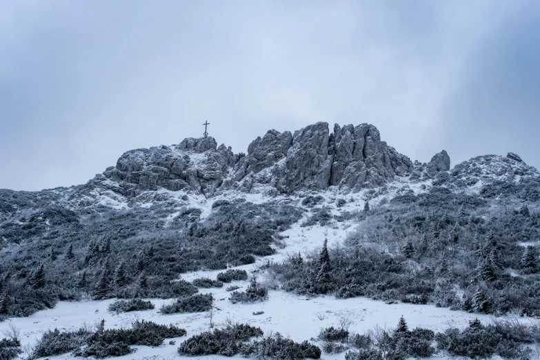 a snow covered mountain top and a cross at the top