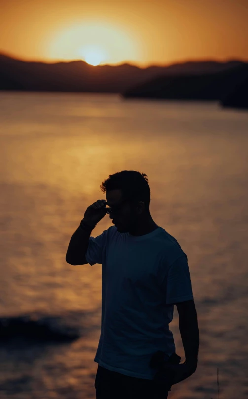 a man is talking on the phone by the water