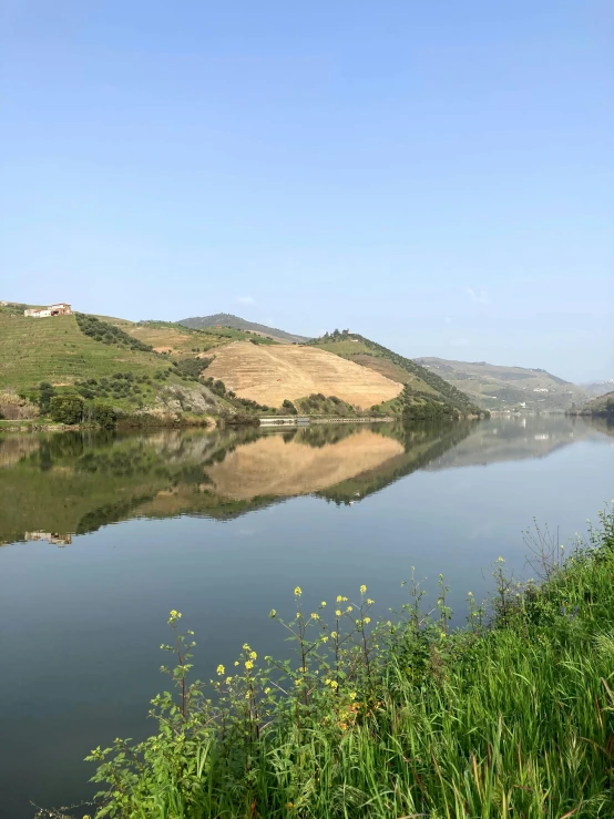 a large body of water surrounded by hills and grass