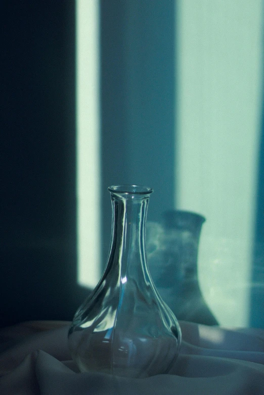 an empty vase and two glass bottles sitting on a table
