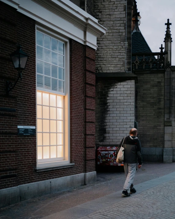 a person carrying a bag is walking down a cobblestone street