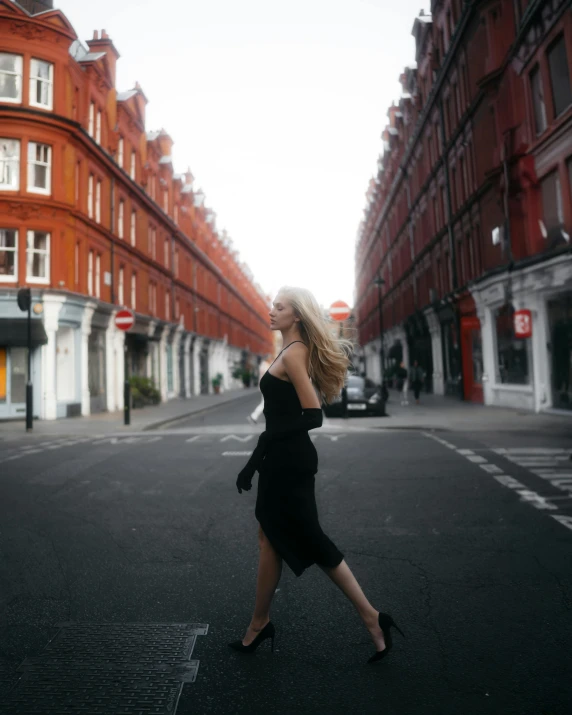 a woman in a black dress walks through a cross walk