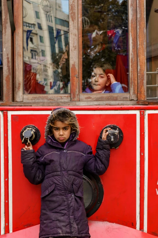 a child in winter gear holding up two black objects