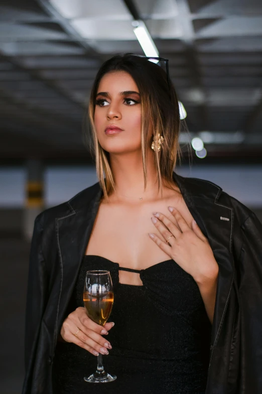 an attractive woman in a black dress holding a glass of wine