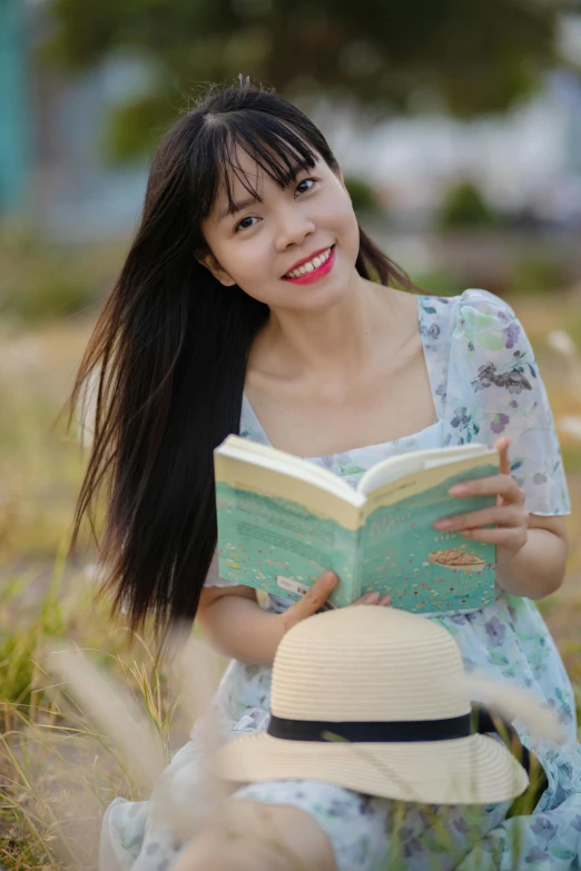 a girl sitting in the grass and reading a book