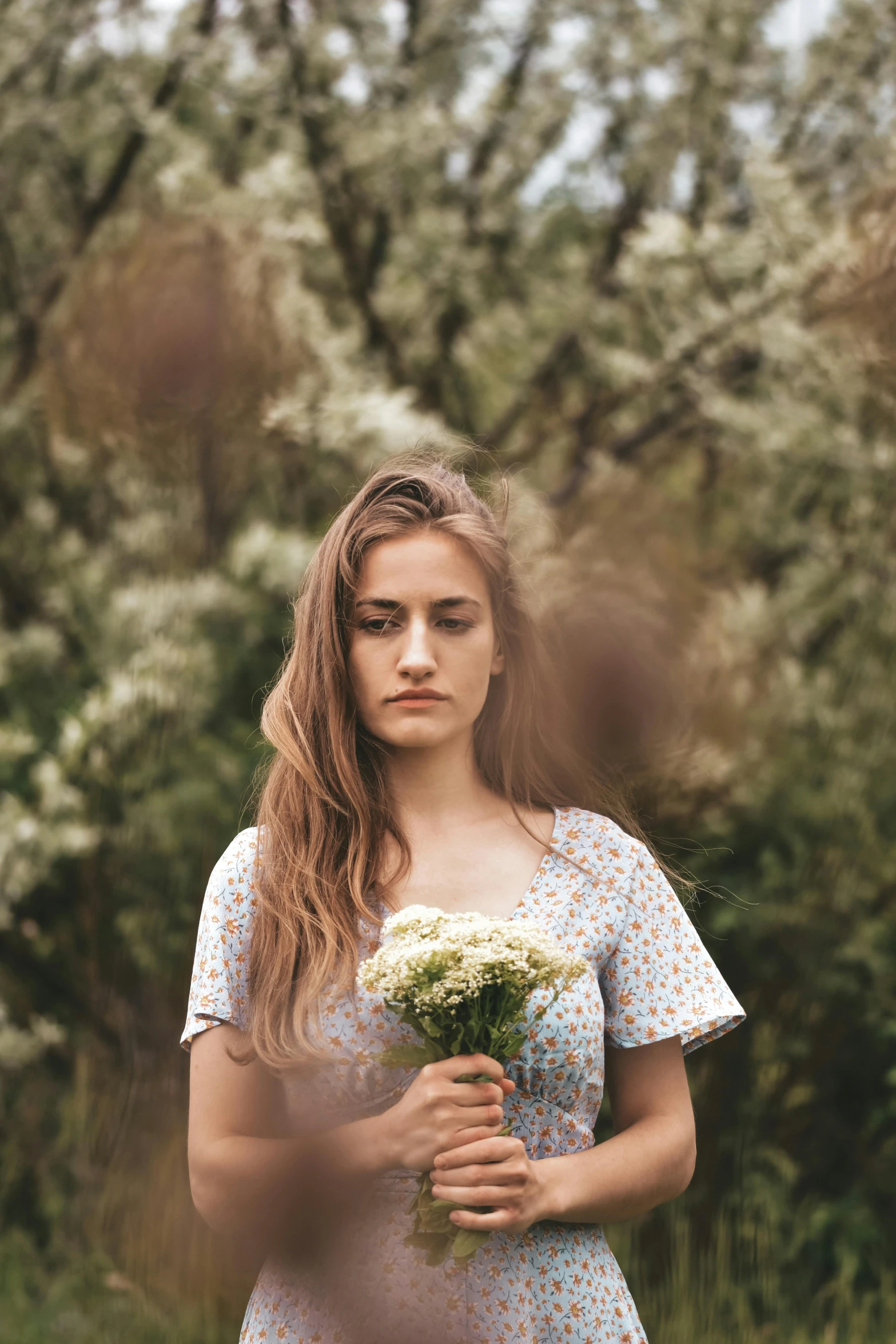 woman with flower in her hand walking through field