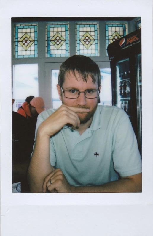 a man sitting down wearing glasses while looking straight ahead