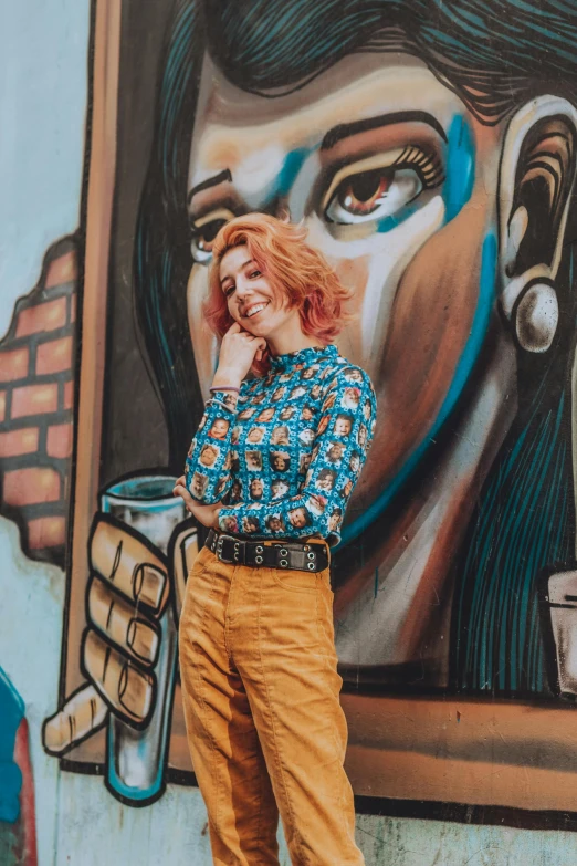 a smiling girl is leaning up against a painted wall