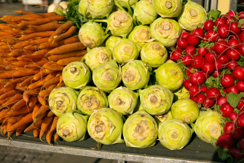 a stand that has carrots, radishes and turnips on it