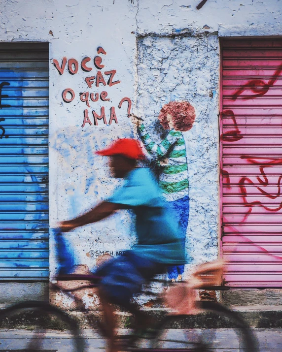 a person riding a bike past a painted wall