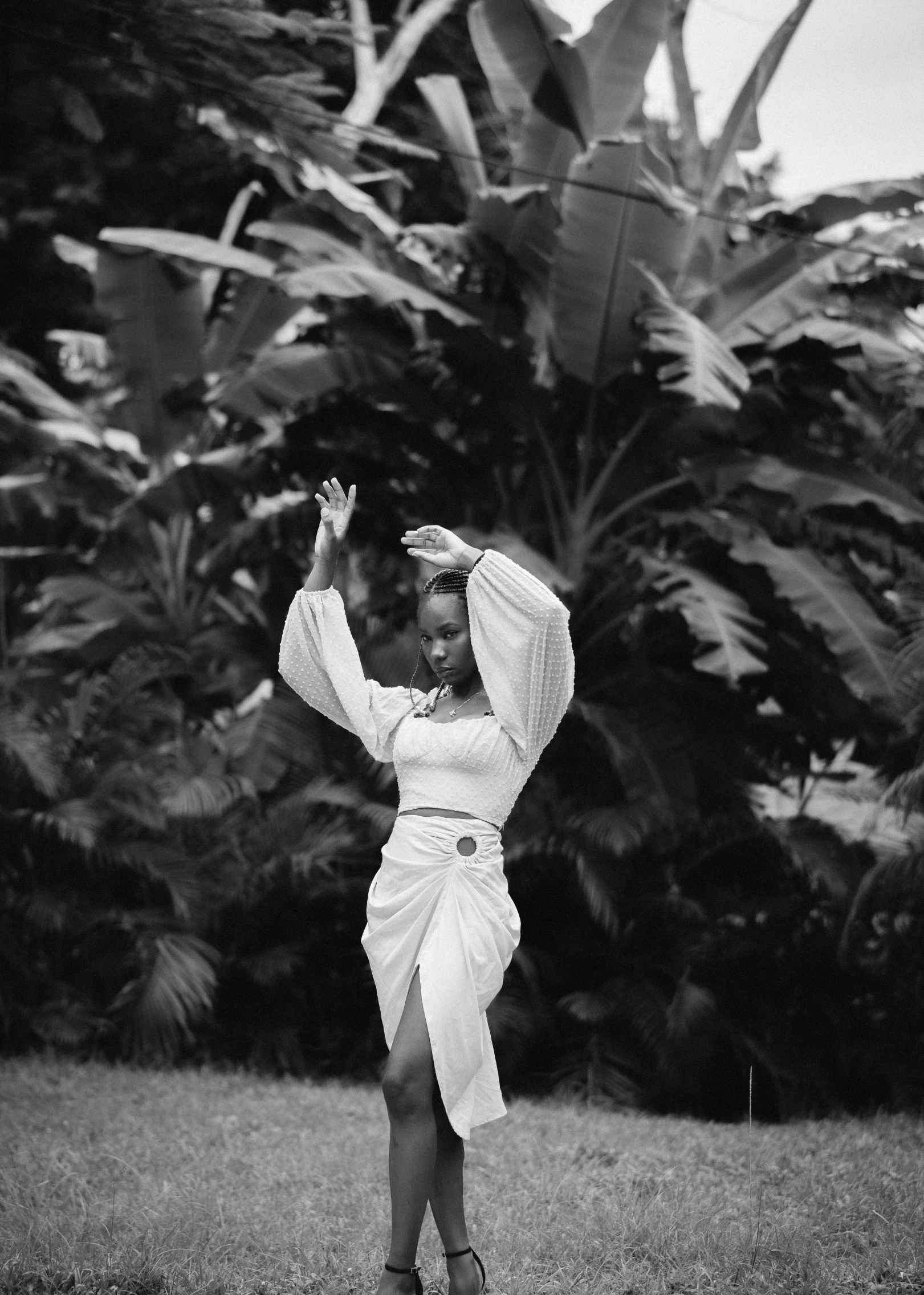 a woman standing in the middle of a yard with her arms in the air