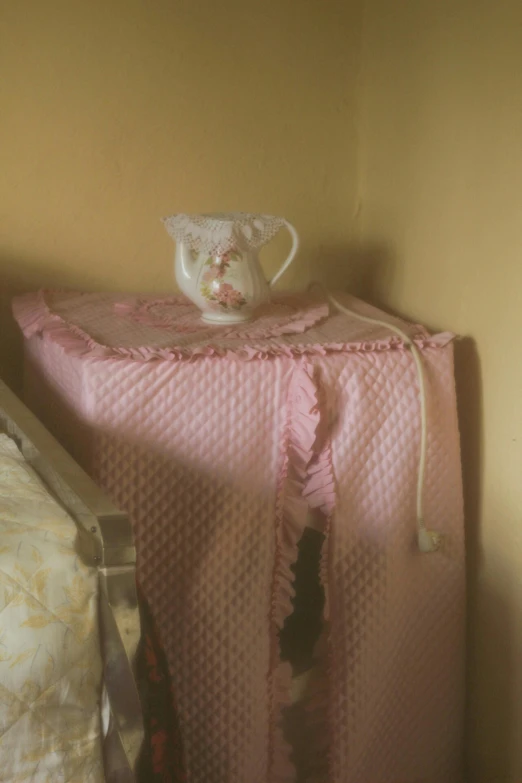 a pink crib has a teddy bear on top