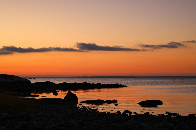 a person is sitting by the water at sunset