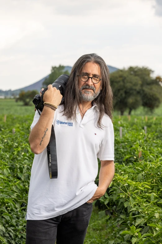 a man holding an umbrella in his hand on a field of plants