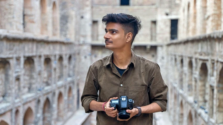 a young man in an alley looking back while holding a camera