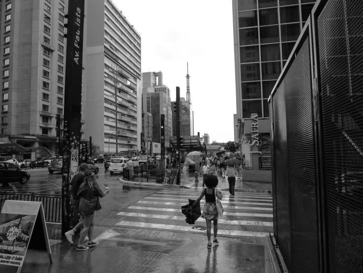 several people walking across the street on a rainy day