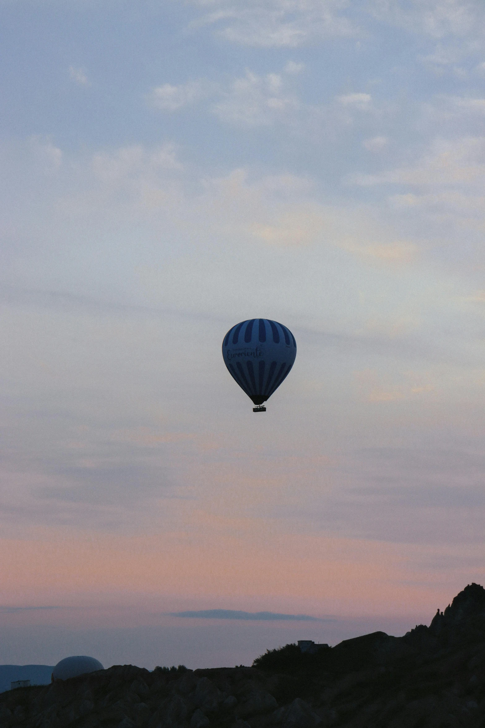 a blue balloon flying over a mountain at sunset